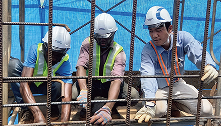 ギニアにおける無償資金協力「国道三号線スンバ橋架け替え計画」において、インターンとして参加する現地の学生に対し、鉄筋の組立てを指導する日本人技術者（写真：大日本土木株式会社）