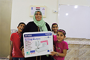 ブラザー社のミシンを受け取る女性とこどもたち（写真：UNDPイラク事務所）
