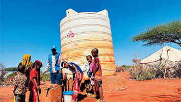 日本の支援によってエチオピアの難民居住区に設置されたタンクで水を汲む難民の家族（写真：UNHCR）