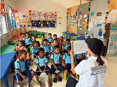 東ティモールでこどもたちに環境教本の読み聞かせを行うJICA海外協力隊員（写真：JICA）