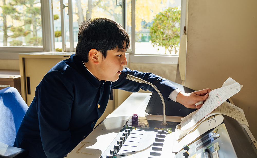 Alex reading the school's announcement in the broadcast room