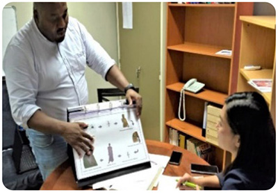 A photo of a member of an evaluation team receiving an explanation of picture cards used to raise awareness of malaria prevention at the Malaria Control Center in Limpopo Province