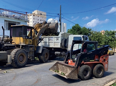 A photo of Disaster waste removal in progress: Dump truck and skid steer loader