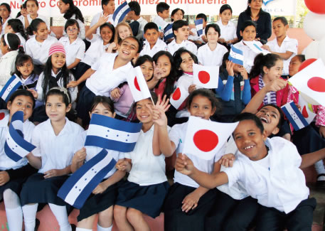 Children wave the flags of Honduras and Japan at a handover ceremony for the “Project for Extension and Renovation of Japon School, Tegucigalpa” supported through the Grant Assistance for Grass-Roots Human Security Project in Tegucigalpa, the capital of Honduras. (Photo: Hiromi Sakai / Embassy of Japan in Honduras)