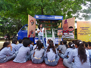 Children enjoying the picture book read to them in front of the campervan (Photo: Kodansha)
