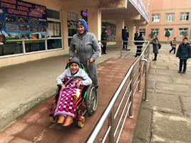 A student with disabilities and her mother using the renovated entrance ramp with a donated wheelchair (Photo: AAR Japan)