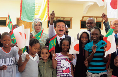 Former State Minister for Foreign Affairs SATO Masahisa surrounded by children at an elementary school in Mauritania, constructed with support from Japan (February 2019)