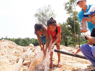 Children of the neighborhood gathering around the clear water provided by the test run of drinking water equipment installed by Tohkemy Corporation in Laos(Photo: Tohkemy Corporation)