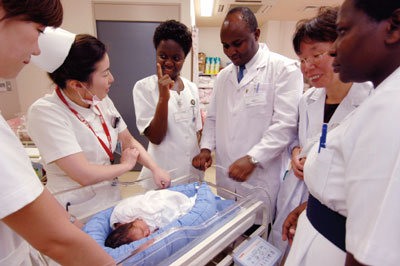 Researchers studying a bed for infants designed to replicate sensations in the womb (June 30, Takatsuki Hospital, Takatsuki City; Source: Kenshiro Imai/JICA)