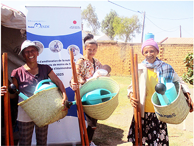 The objects in the women's hands are farming tools for home vegetable gardens that were distributed through a project to support improved child nutrition. “I look forward to using it for field work. I hope to grow leafy greens to give to my kids,” she says with a smile. (Madagascar; Photo: AMDA Multisectoral & Integrated Development Services)