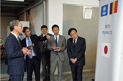 Vice President of the House of Councillors NAGAHAMA Hiroyuki (foreground left) and others receive an explanation from Pablo Zapata, the Acting representative of UNHCR Romania, on how Japan's support is being used at a Ukrainian displaced persons support center (September 4, Bucharest, Romania; Photo: UNHCR Romania)